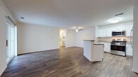 This renovated single-story unit offers a thoughtfully designed open-concept layout that maximizes the generous living space. The entryway welcomes residents with wood-style flooring and a paneled front door with a sidelight that draws in natural light.

The living area is spacious and bright, featuring dark wood-style plank flooring and a ceiling fan overhead. A peninsula with granite-style countertops visually connects the living space to the kitchen, creating a seamless flow ideal for entertaining. The kitchen is well-appointed with crisp white shaker cabinetry, granite-style countertops, stainless steel appliances including a gas range, microwave, dishwasher, and refrigerator, complemented by wood-style flooring.

A sliding glass door in the living area provides direct outdoor access and fills the room with natural light and exterior views. The bedroom features plush carpeting and neutral walls, offering a quiet and comfortable retreat.

The full bathroom is clean and modern, featuring a white vanity with ample storage, a large mirror with accent lighting, and a full tub-shower combination. Wood-style flooring ties the bathroom's aesthetic to the rest of the unit, contributing to a cohesive, updated feel throughout.