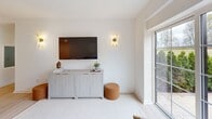 Located at 1188 King St in Greenwich, Connecticut, this thoughtfully designed one-bedroom, one-bathroom residence offers a refined living experience through clean lines, modern finishes, and a cohesive neutral palette throughout. The living room is bright and welcoming, featuring large windows that frame outdoor greenery and fill the space with natural light. Light-toned carpeting and crisp white walls create a calm, airy ambiance well-suited for relaxing or entertaining. The kitchen is sleek and functional, outfitted with high-gloss white cabinetry, a smooth induction cooktop, integrated stainless steel appliances, and light hardwood flooring — a polished, contemporary workspace. The bedroom is a serene retreat, offering dual windows with garden views, ample closet space with double built-in wardrobes, light wood floors, and elegant gold-accent wall sconces that add a warm, sophisticated touch. The bathroom is a standout feature, showcasing a walk-in glass-enclosed shower with marble flooring, wood-toned wall panels, a rainfall showerhead, and an illuminated vanity mirror paired with a warm wood vanity — a spa-like finish of exceptional quality. Throughout the residence, the design balances modern minimalism with inviting warmth, resulting in a polished and comfortable home.