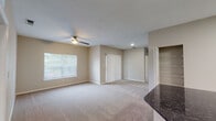 This single-floor residence offers a thoughtfully designed open-concept layout that seamlessly connects the kitchen and living area. The kitchen is a standout feature, showcasing dark granite countertops, crisp white shaker-style cabinetry, stainless steel appliances including a refrigerator, range, and microwave, a tile backsplash, and a peninsula with a stainless steel sink that opens to the main living space. Tile flooring in the kitchen transitions smoothly to plush carpeting throughout the spacious living room, which is equipped with a ceiling fan and benefits from generous natural light through large windows and a sliding glass door with vertical blinds. The bedrooms are well-proportioned, each with soft carpeting, ceiling fans, and sizable windows that invite natural light. The bathrooms are finished with light tile flooring, white vanity cabinetry, warm countertops, large mirrors, and a full bathtub and shower combination. A dedicated in-unit laundry area with overhead shelving adds everyday convenience. The overall aesthetic is clean and neutral, with textured walls and a warm, inviting ambiance throughout.