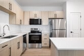 This thoughtfully designed 2-bedroom, 2-bathroom single-floor home in Idaho Falls, Idaho offers a clean, modern aesthetic throughout. The open-concept kitchen and living area serves as the heart of the home, showcasing light wood cabinetry with matte black hardware, crisp white quartz countertops, a central island, and a full suite of stainless steel appliances including a refrigerator, range, microwave, and dishwasher. Light hardwood-style flooring flows through the main living areas, enhancing the bright, airy feel complemented by recessed lighting throughout. The living area provides direct access to a private patio, adding convenient outdoor space. Both bedrooms are carpeted for comfort, featuring neutral tones and window blinds that allow natural light while maintaining privacy. The primary bedroom is generously sized and well-appointed. The two bathrooms mirror the home's consistent design language, featuring light wood vanities, white quartz countertops, large mirrors, and hardwood-style flooring. One bathroom includes a tub-shower combination with white subway tile surround. Additional highlights include a dedicated laundry area, abundant closet storage with five closets throughout, and a clean, move-in-ready condition that reflects quality new construction.