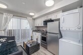 Located at 3352 W 52nd St in Los Angeles, CA, this thoughtfully designed studio maximizes every square foot with a smart, open-concept layout. The combined kitchen and living area is the heart of the space, featuring light wood-look flooring, flush-mount ceiling lights, and a wall-mounted mini-split HVAC unit for year-round comfort. A striking slatted wood divider panel adds architectural depth, visually defining the dining area from the living space, which is anchored by a stylish sofa, marble-top coffee table, and wall-mounted television.

The kitchen is well-appointed with white shaker-style cabinetry, subway tile backsplash, dark stone countertops, and a full suite of stainless steel appliances including a range and refrigerator. A stacked washer and dryer unit is neatly integrated into the kitchen area. Vertical blinds along a sliding glass door flood the space with natural light and provide access to the exterior.

The bathroom features a bold, dark textured accent wall paired with light wood-look flooring, a wall-mounted sink with a vanity mirror, and clean white fixtures — offering a striking contrast of tones. The overall aesthetic throughout is modern and cohesive, blending functional design with contemporary style.