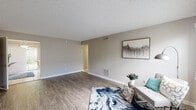 This single-floor residence offers a thoughtfully designed layout that balances open communal spaces with comfortable private quarters. The living room is a generous, light-filled area finished with wood-look laminate flooring, neutral gray walls, and a textured ceiling. A window allows natural light to fill the room, creating a welcoming atmosphere, while a sliding glass door provides direct access to an outdoor green area.

The kitchen is a functional and attractive space, featuring white shaker-style cabinetry, dark wood-tone countertops, and a dual-basin stainless steel sink. Black appliances and a stainless steel refrigerator complement the cabinetry, while tile flooring adds a clean, practical touch. A skylight overhead brightens the room naturally, and a peninsula with bar seating offers a casual dining option.

Both bedrooms are spacious with wood-look laminate flooring, ceiling fans, and generous closet space, including walk-in options. Natural light filters through blinds, and neutral tones throughout maintain a calm, cohesive feel.

The two full bathrooms are finished with wood-tone vanity counters, white cabinetry, large mirrors, and tub-shower combinations, providing practical and clean accommodations throughout.