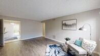 This single-floor residence offers a thoughtfully designed layout that balances open communal spaces with comfortable private quarters. The living room is a generous, light-filled area finished with wood-look laminate flooring, neutral gray walls, and a textured ceiling. A window allows natural light to fill the room, creating a welcoming atmosphere, while a sliding glass door provides direct access to an outdoor green area.

The kitchen is a functional and attractive space, featuring white shaker-style cabinetry, dark wood-tone countertops, and a dual-basin stainless steel sink. Black appliances and a stainless steel refrigerator complement the cabinetry, while tile flooring adds a clean, practical touch. A skylight overhead brightens the room naturally, and a peninsula with bar seating offers a casual dining option.

Both bedrooms are spacious with wood-look laminate flooring, ceiling fans, and generous closet space, including walk-in options. Natural light filters through blinds, and neutral tones throughout maintain a calm, cohesive feel.

The two full bathrooms are finished with wood-tone vanity counters, white cabinetry, large mirrors, and tub-shower combinations, providing practical and clean accommodations throughout.