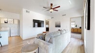 This well-designed single-floor residence offers a clean, contemporary aesthetic defined by crisp white walls, light wood-look flooring, and an abundance of natural light. The open-concept living area serves as the heart of the home, featuring elevated ceilings, a ceiling fan, and a wall-mounted flat-screen television. Large windows and a glass patio door flood the space with daylight while providing direct access to a private outdoor patio, perfect for relaxing or entertaining.

The dining area is anchored by a stylish pendant chandelier and a generous window framing outdoor views, creating a bright and inviting atmosphere for meals. The kitchen is equipped with white cabinetry, granite countertops, black appliances, and a breakfast bar, offering both functionality and style. A dedicated in-unit laundry closet with a full-size washer and dryer adds everyday convenience.

The bedrooms are comfortably sized, featuring plush carpeting and ample natural light from well-placed windows. The bathroom is thoughtfully finished with white vanity cabinetry, granite countertops, and a lighted mirror, continuing the home's cohesive modern design. Throughout, the layout is practical and efficient, making excellent use of space while maintaining a warm and inviting ambiance.