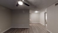 This single-floor unit offers a clean, modern aesthetic with consistent finishes carried throughout every room. The living areas are finished with warm-toned luxury vinyl plank flooring that extends seamlessly across the space, complemented by neutral gray walls, crisp white baseboards, and textured ceilings. Ceiling fans with integrated lighting are present in the main living area and multiple bedrooms, providing both comfort and illumination.

The kitchen is a standout feature, designed in a galley layout with white shaker-style cabinetry, light stone countertops, and a classic white subway tile backsplash. Stainless steel appliances — including a refrigerator, range, and over-the-range microwave — add a contemporary touch, while a deep stainless steel sink with a brushed nickel faucet anchors the workspace.

The bedrooms are generously proportioned, each equipped with a ceiling fan and windows dressed with horizontal blinds that allow for natural light and privacy. The rooms provide a calm, neutral backdrop adaptable to various uses.

The bathroom is straightforward and functional, featuring a full tub-shower combination with clean white surround, a toilet, and wood-look flooring that ties in with the rest of the unit. Brushed nickel fixtures and hardware provide a cohesive, modern finish throughout the space.