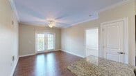 Located in Whitsett, NC, this well-appointed 3-bedroom, 2-bathroom single-floor residence offers a comfortable and functional layout. The open-concept living, dining, and kitchen area serves as the heart of the home, with rich hardwood-style flooring flowing throughout the main living spaces. The kitchen is outfitted with dark espresso cabinetry, granite countertops, stainless steel appliances including a refrigerator, range, and over-the-range microwave, and a breakfast bar that adds casual dining convenience. The living room is bright and inviting, featuring crown molding, a ceiling fan, and French doors that open to a private balcony, filling the space with natural light. The three bedrooms are carpeted for comfort, each equipped with ceiling fans. The primary bedroom offers a generously sized walk-in closet with wire shelving. Additional closet space is abundant throughout, with seven closets in total. The two bathrooms include tiled tub-shower combinations with curved curtain rods. A dedicated laundry room with hookups and a utility room add to the home's practicality. Crown molding and consistent finishes throughout lend a polished, cohesive feel to the entire residence.