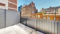 Located at 1314 Spring Garden St in Philadelphia, PA, this thoughtfully designed unit offers a compact yet efficient single-floor layout that maximizes every square foot. The interior opens through a hallway lined with a streamlined galley kitchenette, featuring crisp white cabinetry, open shelving, a black cooktop, and stainless steel appliances — all set against clean white walls and warm wood-tone flooring that runs throughout the space.

The main living area is bright and airy, bathed in natural light streaming through large sliding glass doors that open directly onto a private outdoor patio. Exposed concrete accent walls add an industrial character that contrasts beautifully with the modern finishes. A sleek barn door adds a stylish, space-saving touch to the room's design.

The bathroom is finished to a high standard, featuring large-format light tile flooring, a wall-mounted toilet, a floating vanity with a deep rectangular basin sink, and a walk-in shower — all in a clean, contemporary palette.

The outdoor patio is a standout feature, offering generous tiled space enclosed by modern metal railings with views of Philadelphia's surrounding urban architecture, including charming historic brick buildings. This unit combines modern urban living with thoughtful design details throughout.