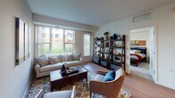 This single-floor, two-bedroom, two-bathroom unit is thoughtfully laid out to maximize functionality and comfort. The living area is bright and welcoming, featuring hardwood-style flooring and large windows that frame outdoor green space views, allowing generous natural light throughout the day. The space flows directly into the kitchen, which is equipped with light wood cabinetry, white appliances including a full-size refrigerator, a double sink, and a peninsula island with seating for casual dining — a practical and social focal point of the space.

Both bedrooms are carpeted and comfortably sized, each offering closet storage. The primary bedroom includes a window with outdoor views, while the second bedroom similarly benefits from natural light. Each of the two full bathrooms features a tub-shower combination, a vanity with wood cabinetry, white countertops, and stone-look tile flooring, providing a clean and consistent aesthetic.

A dedicated in-unit laundry area houses a full-size washer and dryer with overhead shelving for added storage. Throughout, the unit maintains a neutral color palette and a straightforward, functional design suitable for everyday living.