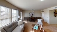 This single-floor residence offers a thoughtfully designed layout that balances comfort and functionality across its key living spaces. The living room serves as the heart of the home, featuring plush carpeting, multiple windows dressed with blinds and sheer curtains that bathe the space in natural light, and direct access to an adjacent dining area. The dining space flows seamlessly from the living room, creating an open, connected atmosphere ideal for everyday living and entertaining. The kitchen is well-equipped, showcasing rich dark cabinetry, granite-style countertops, stainless steel appliances including a French door refrigerator and range, and a peninsula with bar seating that opens to the living area. Both bedrooms are generously proportioned, each featuring soft carpeted flooring, ceiling fans with light fixtures, and windows that invite natural light. The primary bedroom includes access to a private bathroom and a walk-in closet. Both bathrooms are finished with dark wood vanity cabinetry, granite-style countertops, large mirrors, and tub-shower combinations with curtains. The consistent warm, neutral color palette and cohesive dark wood accents throughout give the entire residence a unified and inviting character.