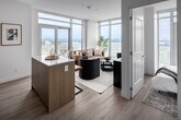 Located on a high floor at 22 Hughson St N in downtown Hamilton, this 2-bedroom, 2-bathroom unit offers a thoughtfully designed open-concept layout with modern finishes throughout. Light hardwood-style flooring flows seamlessly from room to room, complemented by crisp white walls and clean architectural lines.

The living area is a standout, defined by dramatic floor-to-ceiling windows that frame sweeping panoramic views of Hamilton and the waterfront beyond, flooding the space with natural light. The kitchen is sleek and functional, featuring two-tone cabinetry, a white subway tile backsplash, stainless steel appliances, and a central island with bar seating — ideal for casual dining and entertaining.

The primary bedroom is generously proportioned and includes mirrored sliding closet doors and large windows. A second bedroom offers balcony access through glass sliding doors, with expansive city and lake views. Both bathrooms are finished to a high standard; one features a marble-tiled walk-in glass shower, while the second offers a clean, minimalist aesthetic with a white vanity and tub-shower combination.

A bright, art-lined hallway connects all rooms, reinforcing the unit's cohesive and contemporary character. This high-rise residence combines efficient use of space with elevated design and exceptional views.