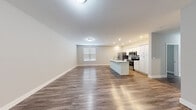 This single-floor residence offers three bedrooms and two bathrooms within a thoughtfully arranged layout. The open-concept living and kitchen area serves as the heart of the unit, featuring warm wood-tone luxury vinyl plank flooring that runs throughout the entire space. The kitchen is equipped with stainless steel appliances, including a refrigerator, microwave, and range, complemented by crisp white cabinetry and a central island with a built-in sink — ideal for both meal preparation and casual dining. Recessed lighting and flush-mount ceiling fixtures provide consistent illumination across the living area, which also benefits from natural light through a window fitted with horizontal blinds.

The three bedrooms are finished with the same consistent flooring and neutral gray walls, offering a clean and versatile backdrop. The primary bedroom provides a comfortable footprint with ample room for furnishings. Both bathrooms feature wood-tone flooring, white vanities with under-sink storage, and well-lit mirrors. One bathroom includes a full soaking tub with an overhead shower. Additional conveniences include a dedicated utility room, a closet for storage, and a connecting hallway that efficiently links all areas of the unit.