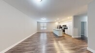 This single-floor residence offers three bedrooms and two bathrooms within a thoughtfully arranged layout. The open-concept living and kitchen area serves as the heart of the unit, featuring warm wood-tone luxury vinyl plank flooring that runs throughout the entire space. The kitchen is equipped with stainless steel appliances, including a refrigerator, microwave, and range, complemented by crisp white cabinetry and a central island with a built-in sink — ideal for both meal preparation and casual dining. Recessed lighting and flush-mount ceiling fixtures provide consistent illumination across the living area, which also benefits from natural light through a window fitted with horizontal blinds.

The three bedrooms are finished with the same consistent flooring and neutral gray walls, offering a clean and versatile backdrop. The primary bedroom provides a comfortable footprint with ample room for furnishings. Both bathrooms feature wood-tone flooring, white vanities with under-sink storage, and well-lit mirrors. One bathroom includes a full soaking tub with an overhead shower. Additional conveniences include a dedicated utility room, a closet for storage, and a connecting hallway that efficiently links all areas of the unit.