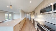 Located at 550 Sheridan Square in Evanston, IL, this well-appointed 2-bedroom, 3-bathroom residence offers a thoughtfully designed single-floor layout with modern finishes throughout. Wide-plank hardwood flooring flows seamlessly across the entire unit, creating a warm and cohesive aesthetic.

The open-concept kitchen and living area serves as the heart of the home. The chef's kitchen features light wood cabinetry with brushed metal hardware, crisp white quartz countertops, a classic subway tile backsplash, and a full suite of stainless steel appliances including a range, dishwasher, refrigerator, and built-in microwave. A generous peninsula with pendant globe lighting connects the kitchen to the living area, which is bathed in natural light through a wall of windows and provides access to a private balcony.

The spacious primary bedroom offers neighborhood views through a large picture window. The second bedroom also features hardwood floors and natural light. Three well-appointed bathrooms include modern vanities with undermount sinks, sleek countertops, and backlit mirrors. A functional hallway features built-in light wood storage cabinetry, enhancing the unit's organizational capacity. Recessed lighting throughout completes the clean, contemporary ambiance of this Evanston residence.