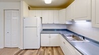 Located at 33 Highland Glen Dr in Randolph, MA, this two-bedroom, one-bathroom residence offers a practical and comfortable single-floor layout. The kitchen is well-equipped with white shaker-style cabinetry extending to the ceiling for generous storage, blue-gray countertops, a stainless steel sink, white appliances including a full-size refrigerator and electric range, and a classic white subway tile backsplash. Durable hardwood-style flooring runs through the kitchen, creating a clean and cohesive look. Both bedrooms feature neutral-toned carpeting and windows that allow natural light to fill the rooms. The spacious primary bedroom includes multiple windows overlooking the surrounding greenery, while the second bedroom offers a comfortable and versatile space. A dedicated closet with wide bi-fold doors provides ample storage. The full bathroom is clean and bright, featuring a tiled shower-tub combination, a white vanity with an integrated sink, and a mirrored medicine cabinet with overhead lighting. A hallway connects the living spaces efficiently. The overall palette of whites and soft neutrals throughout creates a bright, welcoming atmosphere well-suited for everyday living.