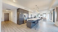 Located at 515 Euclid Ave in the heart of downtown Cleveland, this modern single-floor unit delivers a refined, contemporary living experience defined by clean lines, light-toned luxury vinyl plank flooring, and an open, flowing layout. A bright hallway with recessed ceiling ventilation and a glass-paneled door provides a polished entry into the space.

The open-concept kitchen and living area serves as the centerpiece of the unit. The kitchen is outfitted with two-tone cabinetry—high-gloss charcoal lower cabinets paired with crisp white uppers—and stainless steel appliances including a French door refrigerator, electric range, and built-in microwave. A generous island with a white quartz countertop and seating for multiple bar-height chairs anchors the space and connects seamlessly to the dining and living areas.

The living room is bright and airy, featuring large floor-to-ceiling windows that frame sweeping views of the Cleveland skyline, flooding the room with natural light. The bedroom offers a tranquil retreat with city views, direct access to a walk-in closet with built-in shelving and adjacent in-unit laundry. The bathroom features a warm wood-toned floating vanity and dark vinyl plank flooring for a modern, grounded contrast. Throughout, the unit maintains a cohesive, contemporary aesthetic.