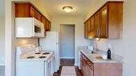 This single-floor, 2-bedroom, 2-bathroom residence in Livonia, Michigan offers a practical and well-finished layout. The entry foyer, finished with rich hardwood-style flooring, leads into the heart of the unit. The galley-style kitchen is thoughtfully designed with warm medium-toned wood cabinetry, granite countertops, a stainless steel sink, and white appliances including a range, over-the-range microwave, refrigerator, and dishwasher. The kitchen opens to a dining area outfitted with a ceiling fan and continued hardwood-style flooring, creating a cohesive, connected space.

A hallway from the main living area provides access to both bedrooms and a closet with built-in rod storage. Each bedroom features plush carpeting and a window that admits natural light and views of the surroundings. The two bathrooms are finished with granite-topped wood vanities and hardwood-style flooring. One bathroom features a glass-enclosed walk-in shower with large-format marble-look tile walls and a mosaic tile floor. Neutral gray wall tones throughout the unit contribute to a clean, modern aesthetic that complements the warm wood finishes.