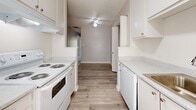This single-floor, 2-bedroom, 2-bathroom home offers a thoughtfully designed layout with a clean, neutral palette throughout. The living room serves as the centerpiece of the space, featuring plush carpeting, a textured ceiling, and a white-surround wood-burning fireplace framed by a large window that floods the room with natural light and offers views of surrounding greenery.

The galley-style kitchen is bright and functional, outfitted with white cabinetry, light stone countertops, white appliances including a range and dishwasher, and light wood-look flooring. A ceiling fan and window add to the airy feel of this space, which flows conveniently toward the dining and living areas.

Both bedrooms are carpeted and generously sized, each benefiting from windows with views of mature trees. The primary bedroom includes a spacious walk-in closet with dual hanging rods, providing ample storage. Additional closets throughout the home further enhance storage capacity.

The bathrooms feature light wood-look flooring, white cabinetry, and stone-look countertops, maintaining the home's consistent, clean aesthetic. A utility room adds practical functionality. Overall, this home presents a bright, move-in-ready interior with well-distributed living spaces and abundant natural light.