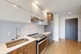 Located at 301 M St SW, Unit 1003 in Washington, DC, this efficiently designed studio offers a thoughtful layout that maximizes every square foot. Light-toned hardwood flooring runs throughout the main living area, which is anchored by two distinctive exposed concrete columns that add an industrial character to the otherwise clean, modern aesthetic. Floor-to-ceiling sliding glass doors open onto a private patio, flooding the space with natural light and offering open views of the surrounding Washington cityscape.

The contemporary kitchen is well-appointed with two-tone cabinetry — gloss white upper cabinets paired with warm wood-grain lower cabinets — complemented by a white subway tile backsplash, light stone countertops, and stainless steel appliances including a range and refrigerator. A dedicated in-unit laundry closet houses a stacked washer and dryer for added convenience.

The bathroom features large-format neutral tile flooring, a wall-mounted wood-grain vanity with a white countertop, a framed mirror, and a marble-tiled shower surround. The entrance includes a closet, completing a practical and cohesive floor plan designed for comfortable urban living.
