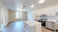 Located at 3295 Burlington Ave N in Saint Petersburg, FL, this single-story 2-bedroom, 1-bathroom home offers a clean, modern aesthetic throughout. Light wood-tone flooring flows seamlessly across the entire living space, creating a bright and cohesive atmosphere. The open-concept kitchen and living area serves as the heart of the home, featuring crisp white cabinetry extending to the ceiling for generous storage, a central island with a white countertop, and a full suite of stainless steel appliances including a range, dishwasher, microwave, and refrigerator. Both bedrooms are comfortably sized, each equipped with ceiling fans and large windows that invite abundant natural light and neighborhood views. The primary bedroom includes a double-door closet with built-in shelving, while an additional closet with wire rack shelving doubles as a dedicated laundry space with washer and dryer hookups. The bathroom features a walk-in shower with large-format white tile surrounds and brushed nickel grab bars. Neutral warm-toned walls and white trim throughout lend a fresh, move-in-ready feel to this thoughtfully designed home.