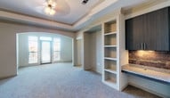 Located at 5201 Collin-McKinney Pkwy in McKinney, Texas, this single-floor residence offers a well-designed layout with a cohesive blend of modern finishes and comfortable living spaces. The kitchen is a standout feature, showcasing rich dark cabinetry, granite countertops, a tile backsplash, stainless steel appliances including a refrigerator, range, and microwave, and a kitchen island with a double stainless steel sink. Light tile flooring runs throughout the kitchen and entry areas, adding a clean, polished look. The open living area flows naturally from the kitchen, featuring plush carpeting, a tray ceiling with crown molding, a ceiling fan, and an elegant arched doorway that leads to a generously sized secondary space with built-in shelving and a balcony access door that invites natural light. The bedrooms are carpeted and equipped with ceiling fans, with one featuring a large window with outdoor views. A spacious walk-in closet with wire shelving provides ample storage. The bathroom is elegantly finished with dark wood cabinetry, a wraparound granite vanity with dual sinks, large mirrors, and a tiled shower-tub combination. Throughout the residence, neutral tones and thoughtful architectural details create a warm, refined ambiance.