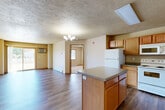 Located at 200 Lorrain Dr in Bismarck, North Dakota, this single-floor, 2-bedroom, 2-bathroom unit offers a well-organized and functional layout. The open-concept kitchen and living area serves as the heart of the home, featuring warm oak cabinetry, a center island with countertop seating space, laminate countertops, white appliances including a range, refrigerator, microwave, and dishwasher, and durable wood-look flooring throughout. A chandelier adds a touch of character above the kitchen area. The living room is bathed in natural light from a large sliding glass door that leads directly to an outdoor patio, offering pleasant outdoor views and easy access to fresh air. Both bedrooms are generously sized with plush carpeting, baseboard heating, and windows that bring in natural light. The spacious primary bedroom provides comfortable accommodations. Each bathroom features wood-look flooring, a tub/shower combination, vanity with storage, and warm neutral tones. A dedicated laundry room with side-by-side washer and dryer hookups and wood-look flooring adds everyday convenience. Neutral wall tones and consistent warm finishes create a cohesive and inviting atmosphere throughout the unit.