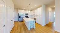 Located at 35205 Tupelo Cir in Frankford, DE, this well-designed single-floor home offers three bedrooms, two bathrooms, and a thoughtful layout that maximizes comfort and functionality. The open-concept kitchen and living area serves as the heart of the home, featuring crisp white shaker cabinetry, a large central island with pendant lighting, stainless steel appliances including a refrigerator, range, microwave, and dishwasher, and light wood-tone flooring that flows seamlessly throughout. The bright, airy kitchen provides ample storage with full-height upper cabinets and open shelving. The bedrooms are well-proportioned, with the primary bedroom offering a ceiling fan and light wood flooring, while the secondary bedrooms feature soft carpet and large windows with open views of the surrounding landscape. Six closets are distributed throughout the home, ensuring generous storage. The bathrooms are finished in a clean, modern style with white vanities, large mirrors, and light flooring. One bathroom includes a tub/shower combination. A dedicated laundry room and utility room add everyday convenience. The home's consistent use of neutral tones and clean lines creates a bright, cohesive ambiance throughout.