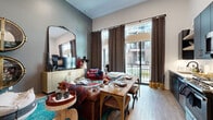 Located at 1300 40th St in Denver, CO, this thoughtfully designed one-bedroom, one-bathroom residence offers a compact yet highly functional single-floor layout. The open-concept living and kitchen area is anchored by a sleek, modern kitchen featuring bold dark cabinetry, stainless steel appliances including a gas range, dishwasher, and full-size refrigerator, complemented by white subway tile backsplash and open floating shelves. Light wood-style flooring runs throughout, enhancing the bright, airy feel created by soaring ceilings.

The living area opens directly to a private balcony through large sliding glass doors dressed with floor-to-ceiling drape panels, allowing abundant natural light and outdoor views. A hallway equipped with a stacked in-unit washer and dryer adds exceptional convenience.

The bedroom features built-in shelving, high ceilings, and a distinctive red accent stripe running along the walls, adding a bold design element. The bathroom is finished with dark cabinetry accented by gold hardware, a white quartz countertop, a framed mirror, and stylish brass vanity lighting. A wide entryway corridor with additional storage completes this well-appointed Denver residence.