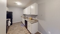 Located at 9 Summertree Ln in Greensboro, NC, this single-story home offers a well-designed layout with clean, updated interiors throughout. The kitchen features crisp white shaker-style cabinetry, dark granite-look countertops, a stainless steel sink, and wood-look flooring, providing a practical and attractive workspace. The living area is carpeted and finished with neutral gray walls, offering a comfortable and versatile space that opens to the outdoors via a large sliding glass door with vertical blinds, allowing for ample natural light and outdoor access. A central hallway connects the main living areas to the bedrooms, each of which is carpeted and painted in soft gray tones. The bedrooms are equipped with ceiling fans, and select rooms feature louvered bi-fold closet doors for convenient storage. The primary bedroom includes direct access to a bathroom with a white vanity, white cabinetry, and well-lit mirror. An additional bathroom includes a single vanity with a white countertop, framed mirror, and bright overhead lighting. Throughout the home, consistent neutral color palettes, textured ceilings, and clean white trim create a cohesive and move-in-ready atmosphere.
