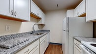 Located at 27261 Westown Blvd in Westlake, Ohio, this single-floor unit offers a practical and straightforward layout designed for comfortable everyday living. The entry opens into a spacious main living area finished with neutral-toned wall-to-wall carpeting and crisp white walls, creating a clean, bright atmosphere. A distinctive dark brown entry door adds a subtle contrast to the otherwise light interior palette. Structural beam details are visible at the ceiling, lending a modest architectural character to the space.

The galley-style kitchen is efficiently organized, featuring white cabinetry that extends to the ceiling for ample storage, granite-look countertops, a stainless steel sink with a modern pull-down faucet, and wood-look flooring. White appliances — including a refrigerator, dishwasher, and range — are integrated seamlessly into the design.

A generously sized living area benefits from a full-width sliding glass door fitted with vertical blinds, allowing abundant natural light and providing direct access to an outdoor balcony with exterior views. The bedroom areas are carpeted and well-proportioned, with one room featuring a large walk-in closet with double doors, offering substantial storage capacity. Additional windows in the bedrooms bring in natural light while maintaining privacy. Overall, the unit presents a functional, well-organized floor plan suitable for a range of living arrangements.