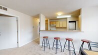 Located at 4300 Collegiate Way in Mount Pleasant, Michigan, this single-floor unit offers four bedrooms and two full bathrooms within a well-organized layout. The open-concept living and dining area is anchored by plush carpeting and natural light from large windows, with a sliding door in the living room providing access to an outdoor balcony area. The kitchen is positioned at the heart of the home, featuring light wood cabinetry, a raised breakfast bar with barstool seating, and essential appliances including a refrigerator, microwave, and dishwasher. A dedicated dining area adjacent to the kitchen accommodates a full-sized table, making it ideal for group meals. A standout practical feature is the in-unit stacked washer and dryer, conveniently located within the kitchen area alongside wood-look flooring. Each bedroom is carpeted and includes a closet and window, offering comfortable, functional spaces suitable for studying and resting. The bedrooms are well-proportioned, with the primary bedroom providing a generous footprint. The two bathrooms are finished with tile flooring, light wood vanities, and a full tub-shower combination. Overall, the unit provides a functional and comfortable living environment well-suited for shared occupancy near Central Michigan University.