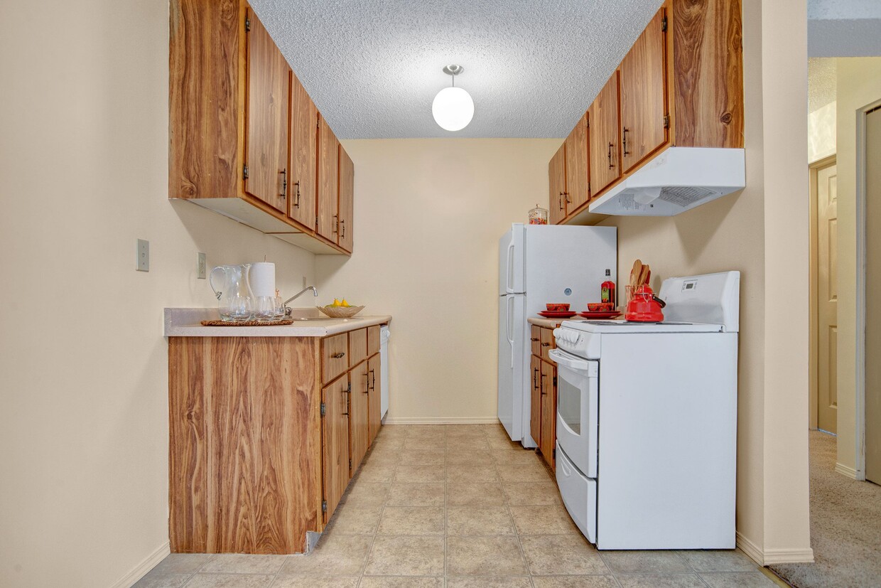 A kitchen with wood cabinetry and overhead lighting - Cedarcrest Manor