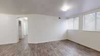 This single-story, 3-bedroom, 2-bathroom home offers a practical and efficiently arranged floor plan designed to maximize every square foot. The combined kitchen and living area serves as the heart of the home, with the kitchen featuring white cabinetry accented by warm wood trim, white appliances including a refrigerator and dishwasher, a built-in sink, and wood-look tile flooring that extends throughout the main living spaces. The living room is bright and open, with natural light filtering in through blinds-fitted windows and clean white walls that lend a fresh, neutral ambiance throughout.

The three bedrooms are thoughtfully sized, with the primary bedroom offering a comfortable retreat. Two of the bedrooms feature soft carpeting, while others continue the wood-look flooring found in the main areas. Each bedroom benefits from natural light through windows with blinds. A dedicated closet with a full-width hanging rod provides convenient storage.

Both bathrooms are finished with wood-look tile flooring, white vanities with countertops, large mirrors, and tub-shower combinations — one featuring white tile surround and the other a molded surround with built-in shelving. Additional spaces include a hallway, a utility room, and a closet, rounding out a complete and functional layout suited for everyday living.