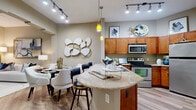 This thoughtfully designed 1-bedroom, 1-bathroom residence offers a functional and stylish single-floor layout. The open-concept kitchen serves as a central hub, featuring warm wood cabinetry, granite countertops, a curved breakfast bar with seating, stainless steel appliances, and hardwood-style flooring. Track lighting and pendant fixtures illuminate the space, adding a modern touch. The kitchen flows seamlessly into a dedicated dining area and the living room, which is highlighted by vaulted ceilings, neutral tones, and a large sliding glass door that invites natural light. The bedroom is a well-sized retreat carpeted for comfort, with windows dressed in blinds and navy curtains, and direct access to a walk-in closet with built-in shelving. The bathroom features warm wood vanity cabinetry, a granite-topped sink, tile flooring, and a shower-tub combination. A hallway connects the main living areas to the private quarters, contributing to an efficient and coherent floor plan. Throughout the residence, neutral wall tones and consistent finishes create a cohesive, welcoming ambiance suited for both relaxed living and everyday functionality.