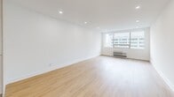 This thoughtfully designed single-floor unit at 2110 offers a clean, contemporary aesthetic throughout. Light hardwood flooring runs continuously across the space, complementing the bright white walls and recessed lighting that create an airy, well-lit atmosphere. Large windows in the main living areas frame urban cityscape views while flooding the rooms with natural light, and built-in HVAC units ensure year-round comfort. The open kitchen is outfitted with modern light wood cabinetry featuring sleek black hardware, stainless steel appliances including a French door refrigerator, dishwasher, and range, as well as a clean white countertop with an under-mount sink. The bathroom is finished to a high standard, showcasing marble-style tile in a glass-enclosed walk-in shower, neutral floor tile, matte black fixtures and hardware, and a stone-topped vanity. A dedicated walk-in closet with built-in shelving and hanging rods provides ample storage. Additional rooms offer versatile, open layouts suited for a bedroom and living area, each maintaining the same consistent, minimalist design language found throughout the unit. The overall ambiance is clean, modern, and move-in ready.