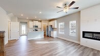Located at 3104 King Ave in Opelika, Alabama, this two-story home offers a thoughtfully designed layout spread across two floors. The main floor serves as the heart of the home, anchored by an open-concept kitchen and living area. The kitchen is well-appointed with white shaker-style cabinetry, granite countertops, a subway tile backsplash, stainless steel appliances, and a central island that provides additional prep and seating space. Wood-look luxury vinyl plank flooring extends throughout the main level, contributing to a clean, cohesive aesthetic.

The living room is a standout space, featuring a floor-to-ceiling shiplap fireplace surround with a sleek linear electric insert, a ceiling fan, and multiple windows that fill the room with natural light. A Craftsman-style front door with transom windows adds character to the entry area.

Upstairs, the bedrooms are carpeted for comfort. The primary bedroom includes its own bathroom, which features a double-sink vanity with granite countertops, white cabinetry, wood-look flooring, and a glass-enclosed walk-in shower. The additional bathrooms are finished with matching granite vanities and tub-shower combinations. Two closets and two hallways support practical storage and circulation throughout the home.