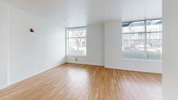 Located in the Crown Hill neighborhood of Seattle, this ground-floor studio unit at 8012 15th Ave NW offers a thoughtfully designed, compact living space with a clean, modern aesthetic throughout. The open-concept main area combines the living room and kitchen into a single bright, airy space, anchored by warm-toned hardwood flooring and crisp white walls that enhance the sense of openness. Large windows along multiple walls allow natural light to flow generously into the room, providing views of the surrounding neighborhood streetscape. The kitchen is well-appointed with dark wood cabinetry, light countertops, stainless steel appliances including a range, microwave, refrigerator, and dishwasher, offering a functional and stylish cooking environment. The bathroom is spacious relative to the unit's overall footprint, featuring accessibility-friendly grab bars, a shower-tub combination, and neutral finishes throughout. The unit's layout is efficient and cohesive, with consistent flooring and a neutral color palette creating a unified, contemporary feel. This unit is well-suited for those seeking a modern, low-maintenance living space in Seattle's vibrant northwest side.