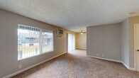 Located at 1600 Aster Dr in Antioch, California, this single-story residence offers a well-organized and functional layout throughout. The open living area is finished with wall-to-wall carpet and features a large window fitted with vertical blinds that allows ample natural light to fill the space. A wall-mounted air conditioning unit provides climate control, and a ceiling fan in the adjacent area adds additional comfort. The entry area is carpeted and includes a built-in heating unit alongside a solid front door.

The kitchen is thoughtfully designed with a U-shaped layout, offering generous counter space with light-toned countertops, two-toned cabinetry featuring white upper cabinets and gray-blue lower cabinets, and wood-look vinyl flooring. It is equipped with a black refrigerator, electric range with overhead ventilation, and a stainless steel sink.

The bedrooms are carpeted and benefit from natural light through windows and sliding glass door access fitted with vertical blinds, offering outdoor views. The bathrooms are cleanly finished with light wood-look flooring, dark vanity cabinetry, white countertops, large mirrors, and brushed nickel fixtures and accessories. The overall design is neutral and move-in ready, presenting a practical and comfortable living environment.