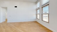 Located at 2580 El Camino Real in Redwood City, CA, Unit 407 is a thoughtfully designed one-bedroom, one-bathroom residence that combines modern finishes with an airy, open layout. Throughout the unit, light-toned hardwood floors and crisp white walls create a clean, contemporary aesthetic. Soaring ceilings amplify the sense of space, while an abundance of windows fitted with slatted blinds draws in generous natural light and frames views of the surrounding neighborhood.

The open-concept kitchen and living area serves as the heart of the unit. The kitchen features sleek white cabinetry with matte black hardware, stainless steel appliances including a refrigerator, range, and microwave, a bright white quartz countertop island with an undermount sink, and under-cabinet lighting. The kitchen flows seamlessly into the expansive living area, which benefits from corner windows and recessed lighting overhead.

The spacious primary bedroom offers multiple windows with city views and ample room to accommodate a full furniture arrangement. Two closets provide generous storage. The bathroom is finished in white with a well-appointed vanity topped with a backlit mirror, white cabinetry with matte black hardware, and a full shower-tub combination. In-unit laundry completes this well-equipped residence.