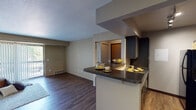 Located at 5220 Hedgewood Dr in Midland, Michigan, this single-floor residence offers a well-designed, open-concept layout that maximizes both functionality and comfort. The living area is spacious and inviting, featuring rich hardwood-style flooring and a large sliding glass door with vertical blinds that fills the room with natural light while providing direct access to an outdoor area. A breakfast bar peninsula connects the living space seamlessly to the kitchen, making it ideal for both entertaining and everyday use. The kitchen is appointed with sleek dark cabinetry, granite-style countertops, track lighting, and black appliances including a refrigerator, stove, and built-in microwave. Hardwood-style flooring continues throughout the kitchen, adding warmth and cohesion to the space. The bedroom is generously sized with plush carpet flooring, a ceiling fan with light fixture, and a window overlooking lush greenery, providing a serene and comfortable retreat. The bathroom features a dark vanity with granite-topped counters, a framed mirror, and a tub-shower combination, all finished with warm, neutral tones. Throughout the residence, neutral wall colors and consistent finishes create a cohesive and modern aesthetic.