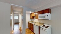 Located on Riddle Road in Cincinnati, Ohio, this single-floor unit offers a straightforward and functional layout well-suited for everyday living. Wood-look flooring runs consistently throughout the space, providing a warm, cohesive aesthetic that ties each area together.

The kitchen is equipped with warm-toned wood cabinetry in two distinct finishes—rich cherry uppers alongside lighter natural wood sections—complemented by granite-look countertops and a stainless steel single-basin sink with a modern pull-down faucet. White appliances include an electric coil range, over-the-range microwave, and dishwasher. A textured ceiling adds dimension overhead.

The living area is open and well-proportioned, featuring a window that brings in natural light and a wall-mounted air conditioning unit. A ceiling fan with an integrated light fixture is present in one of the rooms, alongside a baseboard heater beneath a window—offering year-round climate control options.

The bathroom features tile surrounding the tub-shower combination in a classic white and pink accent pattern, recessed lighting, a vanity with storage, and wood-look flooring that continues from the rest of the unit.

Neutral gray walls throughout the space create a clean, move-in-ready backdrop adaptable to a variety of furnishing styles.
