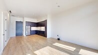 Located at 598 W Main St in Charlottesville, VA, this single-floor unit offers a thoughtfully designed layout with a clean, contemporary aesthetic. Light wood flooring flows continuously throughout the space, complementing the bright white walls and recessed lighting that create an open, airy atmosphere.

The kitchen is a standout feature, outfitted with dark espresso cabinetry extending to the ceiling for generous storage, white countertops, and stainless steel appliances including a refrigerator, electric range, and dishwasher. Under-cabinet lighting adds a polished finishing touch.

The living area benefits from floor-to-ceiling black-framed glass doors that open to a private balcony with metal railings, offering views of surrounding greenery and filling the interior with abundant natural light. The bedroom includes a closet and connects seamlessly to a hallway leading to the bathroom, which features a dark-framed vanity with an undermount sink, stone-tone countertop, and a large backlit mirror. Black hardware accents appear consistently throughout, tying the modern design together. A compact corridor connects all rooms efficiently, maximizing the functionality of the well-proportioned layout.