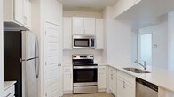 Located at 5959 Cougar Ln in Kearns, Utah, this well-appointed 2-bedroom, 2-bathroom single-floor residence offers a thoughtfully designed layout. The open-concept living, dining, and kitchen area forms the heart of the home, creating a bright and functional shared space. The kitchen is outfitted with crisp white shaker-style cabinetry, light quartz countertops, a stainless steel refrigerator, range, and over-the-range microwave, along with a double basin sink. A pantry provides additional storage conveniently off the kitchen. Light wood-look flooring runs through the main living areas, while plush carpet adds comfort to both bedrooms. The primary bedroom is generously sized and features a ceiling fan with light fixture and a window with blinds for natural light. The second bedroom is equally well-lit with a window. Both bathrooms are finished with white vanities, light countertops, and tub-shower combos. Four closets throughout the home offer abundant storage. A utility room and a balcony round out the functional amenities. A connecting hallway ties the layout together with clean, neutral finishes throughout.
