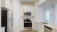 Located at 5959 Cougar Ln in Kearns, Utah, this well-appointed 2-bedroom, 2-bathroom single-floor residence offers a thoughtfully designed layout. The open-concept living, dining, and kitchen area forms the heart of the home, creating a bright and functional shared space. The kitchen is outfitted with crisp white shaker-style cabinetry, light quartz countertops, a stainless steel refrigerator, range, and over-the-range microwave, along with a double basin sink. A pantry provides additional storage conveniently off the kitchen. Light wood-look flooring runs through the main living areas, while plush carpet adds comfort to both bedrooms. The primary bedroom is generously sized and features a ceiling fan with light fixture and a window with blinds for natural light. The second bedroom is equally well-lit with a window. Both bathrooms are finished with white vanities, light countertops, and tub-shower combos. Four closets throughout the home offer abundant storage. A utility room and a balcony round out the functional amenities. A connecting hallway ties the layout together with clean, neutral finishes throughout.