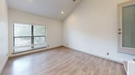 Located at 2800 Douglas Ave in Dallas, Texas, this two-story residence offers a well-designed layout spread across two floors. The main level is generously proportioned, housing two distinct living areas, a kitchen, and a full bathroom. Light-toned wood-look flooring flows throughout, complementing the crisp white walls and creating a clean, cohesive aesthetic. The kitchen is a functional galley-style space featuring white cabinetry, dark granite countertops, a mosaic tile backsplash, and a full suite of stainless steel appliances, including a refrigerator, range, and over-the-range microwave. Recessed lighting and a window bring brightness to the space. The bathrooms are finished with dark granite vanity tops, white cabinetry, and marble-style tile surrounding the tub and shower areas. Upstairs, the spacious primary bedroom impresses with soaring vaulted ceilings and a ceiling fan, filling the room with an airy, open feel. Natural light filters in through slatted window blinds, and a mirrored sliding-door closet provides generous storage. A second living area on the upper level offers additional flexible space. The staircase connects both floors seamlessly, making this a practical and stylish two-story home.
