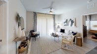 This single-floor residence is designed with a modern, neutral aesthetic that creates a cohesive and inviting atmosphere. The open-concept kitchen serves as a central hub, featuring white cabinetry extending to the ceiling, dark granite countertops, a tiled backsplash, and black appliances including a range, microwave, and refrigerator. A kitchen island with bar seating and pendant lighting anchors the space and connects seamlessly to the main living area. The living room is bright and airy, with light wood-style flooring, a ceiling fan, and large sliding glass doors dressed with patterned curtains that allow for generous natural light.

The multiple bedrooms offer a calm retreat, each finished with neutral walls, ceiling fans, and window treatments providing privacy and light control. Bedrooms include ample storage and present a comfortable, well-proportioned layout.

The bathrooms are cleanly finished, featuring dark granite countertops, white cabinetry, and light wood-style flooring. The primary bathroom includes a glass-enclosed walk-in shower and direct access to a walk-in closet, while the secondary bathroom offers a full tub-shower combination. Overall, the space maintains a consistent, contemporary character throughout.
