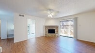 This two-story home offers a well-organized layout spread across two floors of nearly equal size. The main level features an open living area with warm hardwood-style flooring, a textured ceiling, and a ceiling fan that keeps the space comfortable. A standout corner brick fireplace serves as the focal point of the living room, complemented by a sliding glass door that opens to a private fenced outdoor area, filling the space with natural light. Adjacent to the living room, the kitchen is finished with white cabinetry, tile flooring, and white appliances including a range, microwave, and refrigerator, with its own sliding glass door providing additional outdoor access and natural light. A dedicated laundry area with built-in shelving and washer/dryer hookups adds everyday convenience. The two bedrooms are carpeted and generously sized, with the primary bedroom offering notable square footage, ceiling fan, and closet access. Both bathrooms are finished in white tile, featuring tub-shower combinations and white vanities with ample cabinet storage. A closet provides additional storage throughout the home. The clean, neutral palette and functional layout make this a practical and comfortable two-story residence.