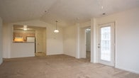 Located at 5700 Magnolia Chase Way in Virginia Beach, Virginia, this single-floor residence offers a well-designed, open layout that maximizes comfort and functionality. The spacious living room serves as the heart of the home, showcasing vaulted ceilings, a ceiling fan with light fixture, plush wall-to-wall carpeting, and a fireplace framed by a clean white mantel. Natural light filters in through multiple windows, and a glass-paneled door provides access to the exterior. Pendant lighting connects the living area to the adjacent dining space, which flows seamlessly into the kitchen. The kitchen is appointed with light wood cabinetry, ample counter space, tile flooring, and a dishwasher, offering a practical and cohesive workspace. The bedrooms are generously sized, each featuring ceiling fans, soft carpeting, and closet storage, with one bedroom offering a large walk-in closet. The bathrooms are finished with light wood vanities, tile flooring, and tub-shower combinations, maintaining a consistent and clean aesthetic throughout. A dedicated laundry room houses a full-size washer and dryer with wire shelving above, adding everyday convenience. The home's neutral color palette and consistent finishes create a bright, inviting atmosphere throughout.