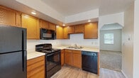 Located at 1935 N Scarlet Maple Ln in Elkhart, Indiana, this single-floor, 2-bedroom, 1-bathroom home offers a practical and comfortable layout. The kitchen is well-equipped with warm oak cabinetry, light countertops, recessed lighting, and black appliances including a range, microwave, and dishwasher. The L-shaped kitchen flows into the adjacent living and dining area, which features light hardwood-style flooring, a chandelier overhead, and a sliding glass door that opens to an outdoor deck with lush greenery views. A dedicated closet space is conveniently positioned nearby. The hallway connects the main living areas to the bedrooms and bathroom. Both bedrooms are carpeted and feature neutral walls, natural light from windows overlooking the outdoors, and closets with wood-toned doors. The primary bedroom offers a comfortable footprint with ample room for furnishings. The bathroom includes a full tub-shower combination with tiled surround accented by a decorative border, hardwood-style flooring, and a vanity with a white countertop. Throughout the home, the clean, neutral palette and consistent finishes create a cohesive and move-in-ready atmosphere.