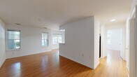 Located at 1404 Esplanade Ct in Reston, Virginia, this single-floor residence offers a clean, functional layout highlighted by warm hardwood-style flooring that runs consistently throughout the space. The open living and dining area is generously proportioned, featuring crisp white walls, multiple windows that invite natural light and views of surrounding greenery, and a partial dividing wall that subtly defines zones while preserving an open feel.

The galley-style kitchen is efficiently arranged with light wood cabinetry lining both sides, white countertops, and stainless steel appliances including a gas range and refrigerator. A skylight overhead brightens the workspace considerably, while a side door provides additional access and natural light. A pass-through connects the kitchen to the main living area, enhancing the overall flow.

The bedroom is a well-sized, quiet room featuring a large window with outdoor views and ample wall space. The bathroom is straightforward and functional, with a wide vanity topped with white countertops, wood cabinetry below, a large wall mirror, and hardwood-style flooring that matches the rest of the unit. The entryway area provides utility access and connects to the various rooms in an organized manner, contributing to the unit's practical and cohesive design.