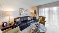 Located at 1403 Kirts Blvd in Troy, Michigan, this single-floor residence offers a thoughtfully designed layout with comfortable living spaces throughout. The living room provides a welcoming atmosphere with plush carpeting, large vertical-blind windows that invite natural light, and tasteful décor including framed artwork and a glass-top coffee table. Adjacent to the living area, the dining space is anchored by a ceiling fan with lighting and features sliding glass doors that open to outdoor views, creating a bright and airy environment. The galley-style kitchen is well-equipped with rich dark wood cabinetry, granite-style countertops, stainless steel appliances including a refrigerator, dishwasher, and microwave, and durable hardwood-style flooring. The residence includes multiple bedrooms, each featuring plush carpeting, large windows with vertical blinds for natural light and privacy, and accent walls that add depth and character. The full bathroom is finished with tile flooring, a tub-shower combination with glass doors, a rich wood vanity with an extended countertop, and clean white tile walls. The overall ambiance throughout the home is warm, neutral, and move-in ready.